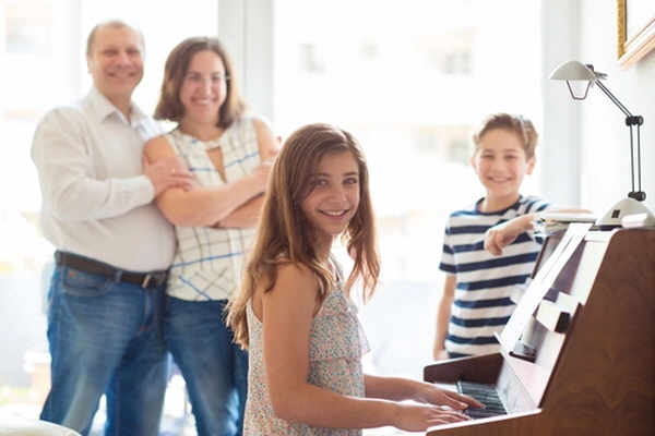 아이들의 피아노 연주를 듣는 행복한 가족.(셔터스톡)