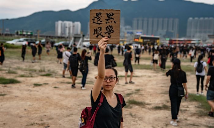 한 여성이 홍콩 국제공항의 시위대에서 해산하며, 공항 밖에서 "경찰은 눈을 되돌려 달라!"는 플래카드를 들고 있다. 2019. 8. 12. | Anthony Kwan/Getty Images