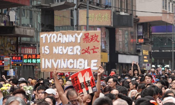 홍콩시위 참가자 한 명이 “폭정은 멸망하기 마련이다”라고 쓴 피켓을 들고 있다. 또다른 참가자는 “어린이는 폭도가 아니다”라는 푯말을 들었다. | Yu Gang/The Epoch Times
