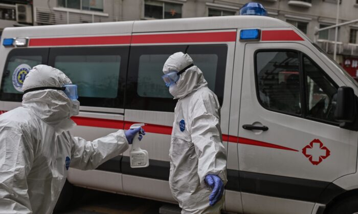 중국 우한 적십자병원에서 한 구급차 의료진이 CCP 바이러스완치 환자를 이송한 동료에게 소독약을 뿌리고 있다. 2020. 3. 30. |  HECTOR RETAMAL/AFP via Getty Images