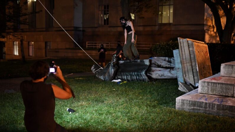 지난 19일 시위대가 미국 워싱턴의 앨버트 파이크 장군 동상을 쓰러뜨린 뒤 그 위에 올라가 고인을 모욕했다. 다른 시위대는 이 장면을 촬영했다. | ERIC BARADAT/AFP via Getty Images