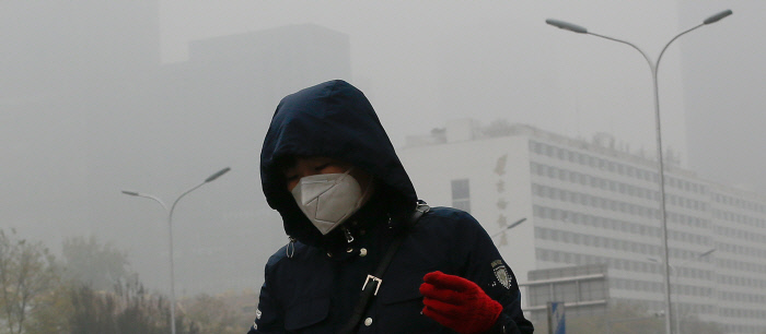 지난 2018년 11월 마스크를 쓴 여성이 먼지와 안개로 뒤덮인 베이징 시내를 걷고 있다. | AP=연합뉴스