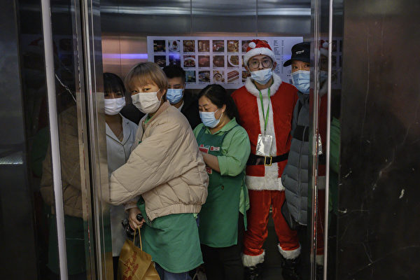 2020년 12월 24일, 중국 베이징의 한 쇼핑몰에서 산타클로스 복장을 한 매장 직원이 마스크를 착용하고 엘리베이터에 탑승해 있다. 이날 이 쇼핑몰에는 휴일 크리스마스를 맞아 많은 쇼핑객이 몰렸다. | Kevin Frayer/Getty Images