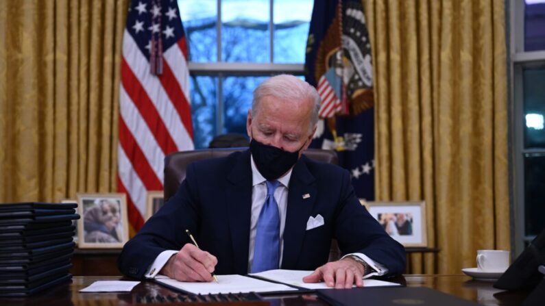 조 바이든 미국 대통령이 취임 첫날 백악관 집무실에서 행정명령서에 서명하고 있다. 그는 이날 17개의 행정명령을 한꺼번에 처리했다. | JIM WATSON/AFP via Getty Images=연합
