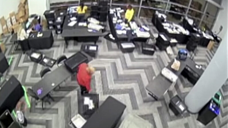 조지아주 풀턴 카운티 CCTV 영상의 한 장면. 빨간 옷을 입은 남성이 탁자 아래에서 상자를 꺼내고 있다. | CCTV 화면 캡처