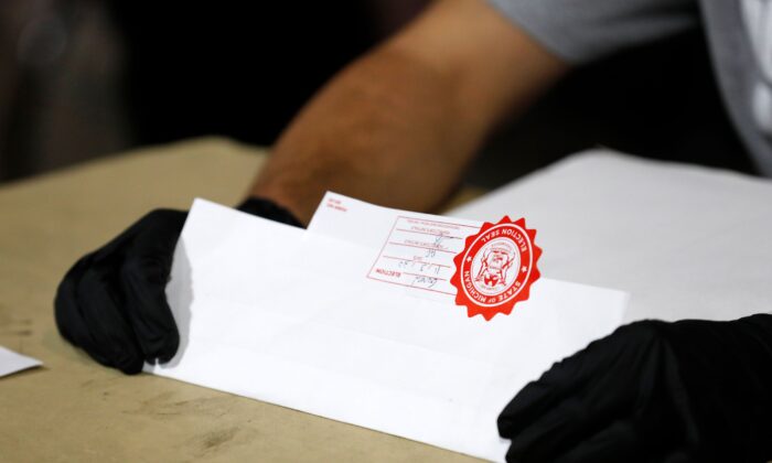 미국 미시간주 디트로이트시의 한 선거 관리 위원이 우편투표 봉투에 적힌 서명이 일치하는지 확인하고 있다. 2020.11.3 | Jeff Kowalsky/AFP via Getty Images