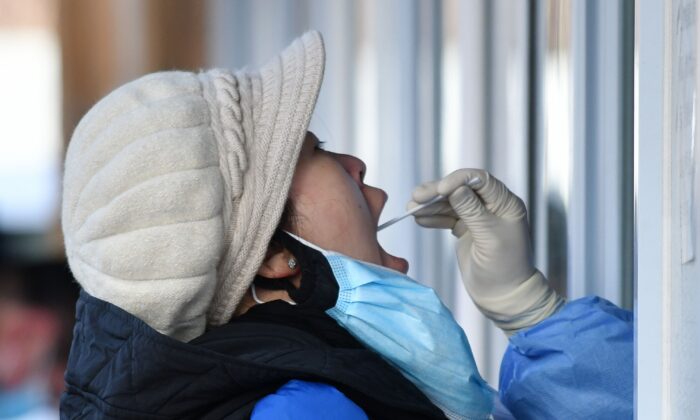 베이징의 한 병원 밖에서 한 여성이 COVID-19 검사를 받고 있다. | Greg Baker/AFP via Getty Images