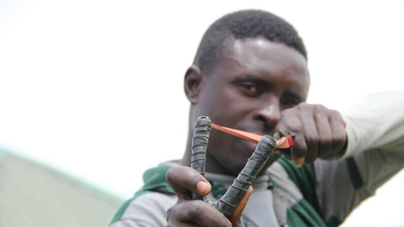 나이지리나 플라테아우 바싸 지역의 한 농경민이 돌격소총으로 무장한 테러범의 기습에 맞서 싸울 때 사용한 무기인 '새총'을 겨냥해 보이고 있다. | 바싸=마사라 킴/에포크타임스