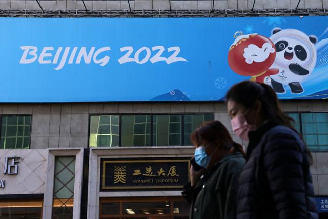 2022 베이징 동계올림픽 개막을 100일 앞둔 지난달 27일 중국 수도 베이징 거리에서 시민들이 올림픽 홍보 배너 앞을 지나고 있는 모습. 베이징 동계올림픽은 내년 2월 4일 개막한다. | 로이터/연합
