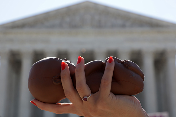 워싱턴 DC 미연방 대법원 앞에서 시민 활동가가 태아 모델을 손에 들고 낙태법을 반대하고 있다. (Alex Wong/Getty Images)
