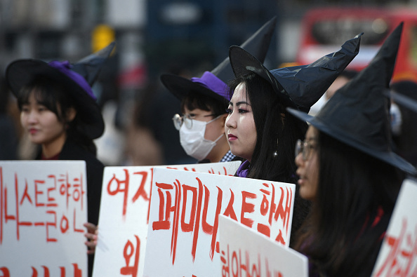 2019년 3월 8일 서울에서 열린 세계 여성의 날 시위에서 마녀 복장을 한 한국 여성들이 페미니즘을 지지하는 현수막을 들고 있다. | JUNG YEON-JE/AFP via Getty Images