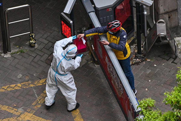 지난 4월 5일, 전면 봉쇄된 상하이시 징안구에서 방호복을 입은 직원들이 아파트 입구에서 물품을 건네받고 있다. | Hector Retamal/AFP