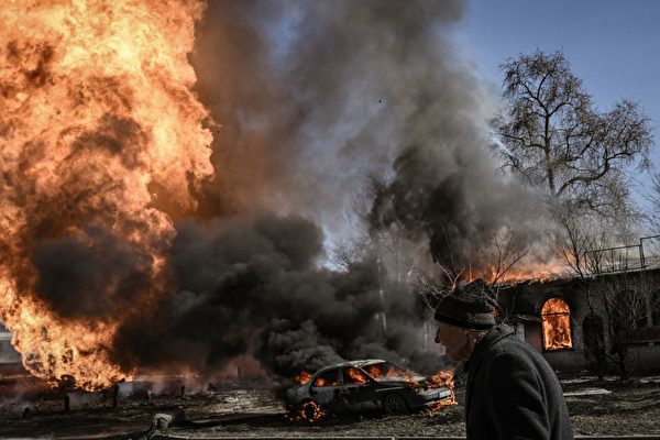 러시아의 우크라이나 침공 30일째인 지난달 25일, 우크라이나 하르키프의 한 지역에서 러시아군의 포격으로 불길과 연기가 솟아오르는 가운데, 한 여성이 지나가고 있다. 2022.3.25 | Aris Messinis/AFP/연합