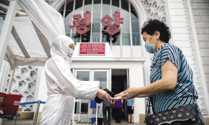 북한 평양역 앞에서 방역복을 입은 북한 방역 요원이 주민들 손에 소독제를 짜주고 있다. | 연합뉴스