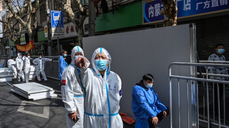 2022년 3월 15일 중국 상하이의 한 봉쇄지역 출입구에 차단벽이 설치된 가운데 방호복을 입은 경찰관이 사진 촬영을 제지하는 손짓을 하고 있다. | Hector Retamal/AFP via Getty Images=연합뉴스
