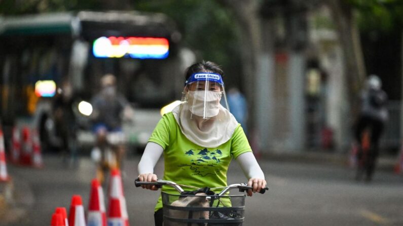 중국 상하이의 통제구역에서 얼굴 보호 가림막과 마스크를 착용한 중국인 여성이 자전거로 어딘가 이동하고 있다. 2022.7.16 | HECTOR RETAMAL/AFP via Getty Images=연합뉴스
