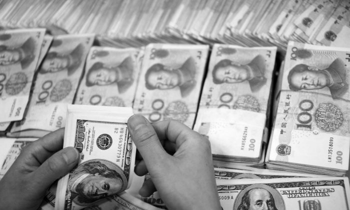 중국 안후이성 화베이의 한 은행에 100위안 뭉치가 놓인 가운데 한 은행원이 달러화를 세고 있다. 2014.9.23 | STR/AFP/Getty Images