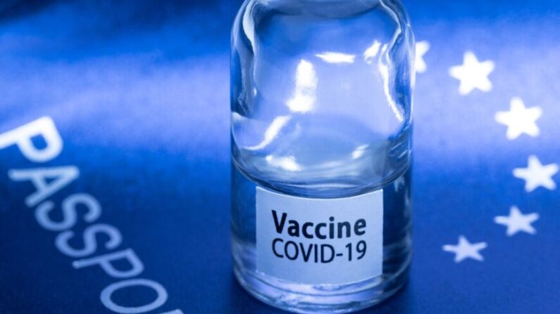 유럽 여권 위에 코로나19 백신이라고 적힌 종이가 붙은 병이 놓여 있다. |  JOEL SAGET/AFP via Getty Images/연합뉴스