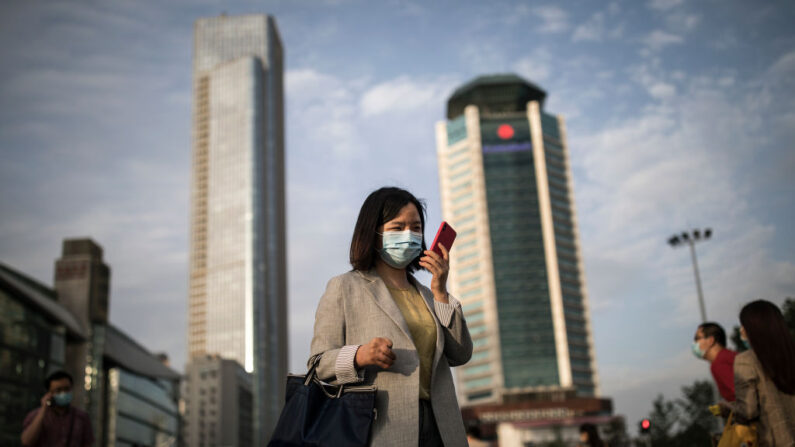 중국 후베이성 우한시의 한 거리에서 코로나19 방역 정책에 따라 마스크를 착용한 시민이 스마트폰을 조작하며 걷고 있다. 2020.11 | Getty Images