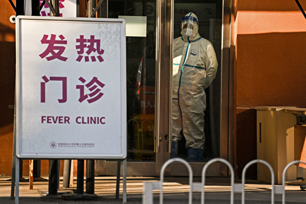 보호복을 입은 보안 요원들이 베이징에서 사람들이 많이 몰리는 한 코로나19 진료소 앞에 경비를 서고 있다. 2022.12.28 | Noel Celis/AFP/연합뉴스