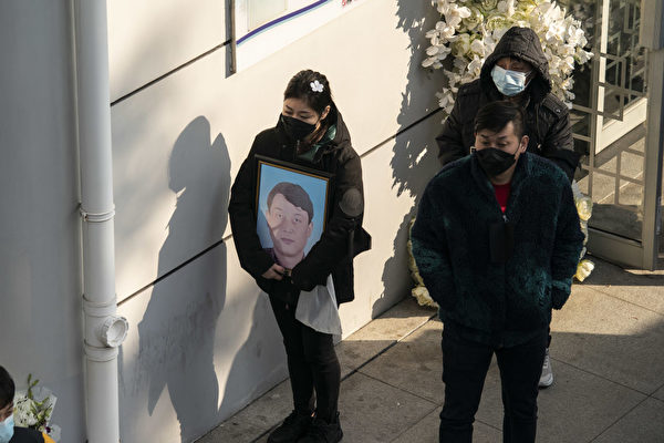 중국의 한 장례식장 앞에 사망자의 영정 사진을 든 가족이 다른 조문객과 함께 서 있다. | Qilai Shen/Bloomberg via Getty Images