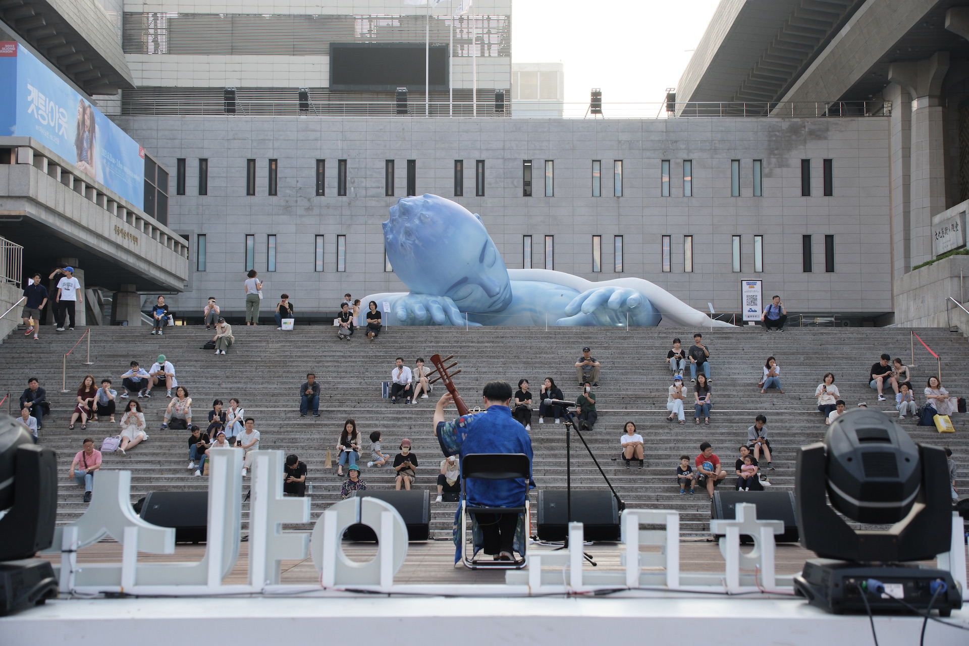 시민들이 세종문화회관 야외 계단에 앉아 비파 연주자 마롱의 공연을 감상하고 있다. | 박재현/에포크타임스