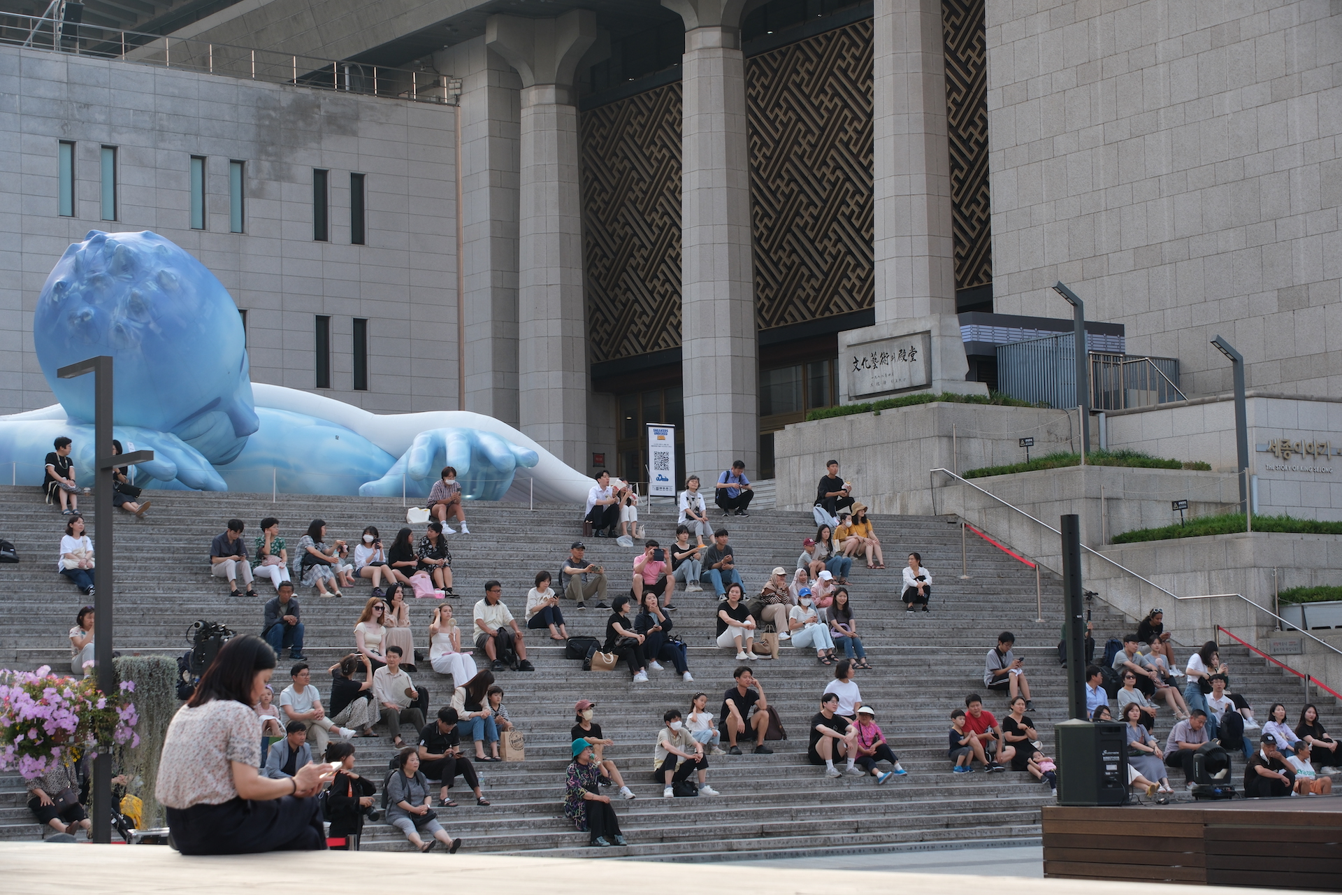 시민들이 세종문화회관 야외 계단에 앉아 '문화가 흐르는 예술마당' 공연을 감상하고 있다 | 박재현/에포크타임스