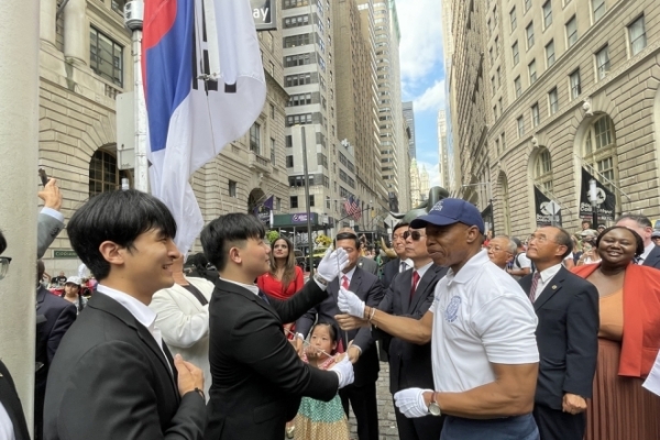 8월 14일(현지시간) 미국 뉴욕 월스트리트의 '돌진하는 황소상' 앞에서 에릭 애덤스 뉴욕시장(오른쪽)이 브라이언 전 AAYC 회장과 태극기를 게양하고 있다. | 연합뉴스