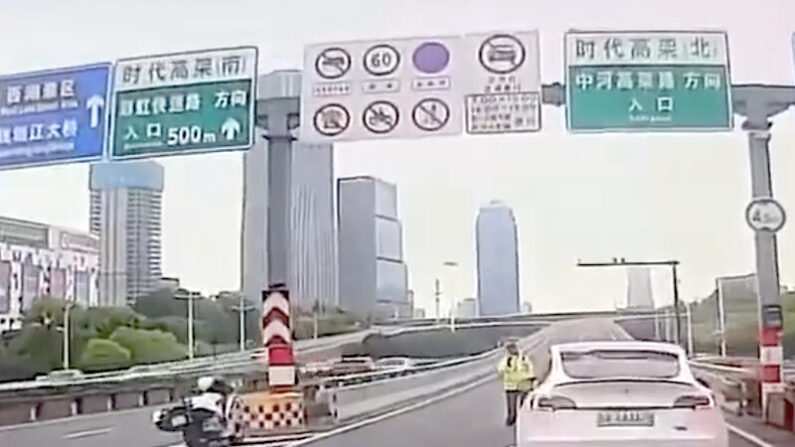 중국 공산당 간부가 탑승했을 것으로 추정되는 고급 승용차를 앞지른 흰색 테슬라 차량이 고가도로 진입로에서 경찰에 붙잡혀 있다. | 소셜미디어 화면 캡처