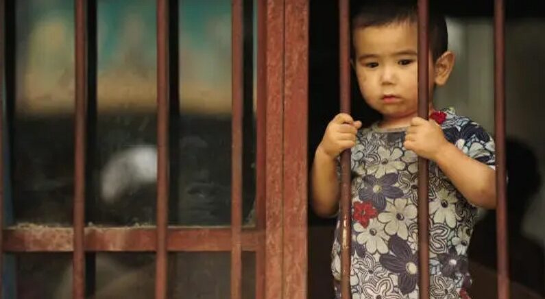 2009년 7월 12일, 한 위구르족 소년이 중국 신장 지역 우루무치시에 있는 자신의 집에서 외부를 내다보고 있다. | Peter Parks/AFP via Getty Images