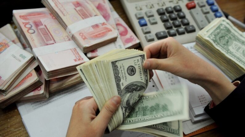 중국 동부 안후이성 허페이의 한 은행에서 은행원이 미국 달러와 중국 100위안 지폐 더미를 세고 있다. | STR/AFP via Getty Images/연합뉴스