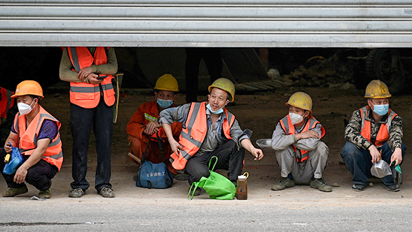 베이징의 한 거리, 셔터 아래 앉아 있는 노동자들(기사 내용과 관련 없는 사진). | NOEL CELIS/AFP via Getty Images=연합