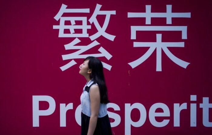 2015년 7월 28일, 중국 베이징에서 한 여성이 한자로 '번영'이라고 적힌 보드판 옆을 지나고 있다. | Fred Dufour/AFP/Getty Images/연합뉴스