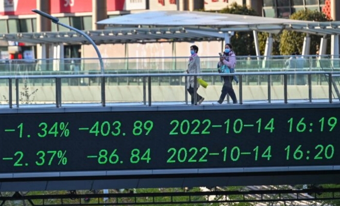 2022년 10월 17일, 중국 상하이의 루자쭈이 금융 지구에서 사람들이 다리를 건너는 가운데 주가 표시 전광판이 보인다. | Hector Retamal/AFP via Getty Images/연합뉴스