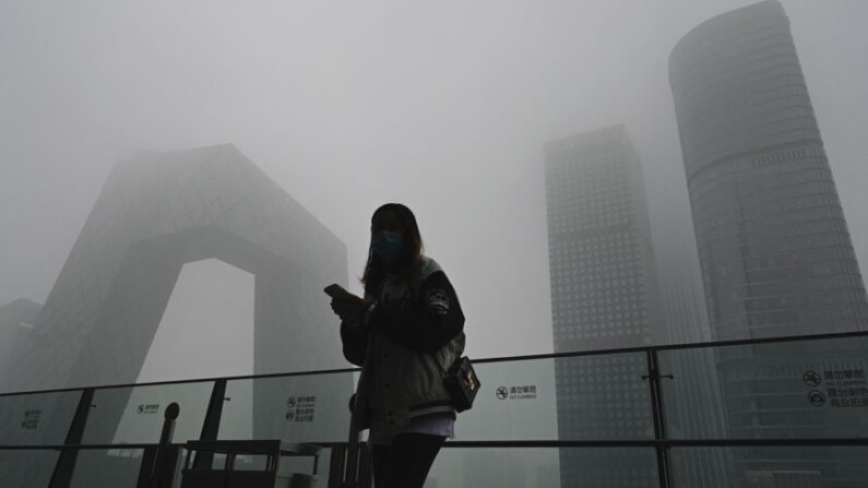 중국 베이징의 중국중앙(CC)TV 본사 건물 주변에서 한 여성이 유리 난간에 기대어 휴대전화를 사용하고 있다. | JADE GAO/AFP via Getty Images/연합뉴스