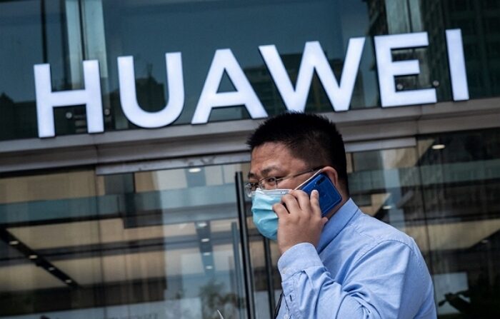 중국의 한 도시에서 남성이 스마트폰을 사용하고 있는 가운데 화웨이의 로고가 보인다. | 연합뉴스