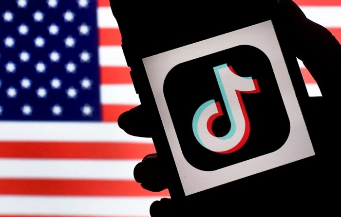 중국 기업 바이트댄스가 운영하는 소셜미디어 틱톡의 로고가 아이폰 화면에 표시된 가운데, 그 뒤로 미국 국기가 보인다. | Olivier Douliery/AFP via Getty Images/연합뉴스